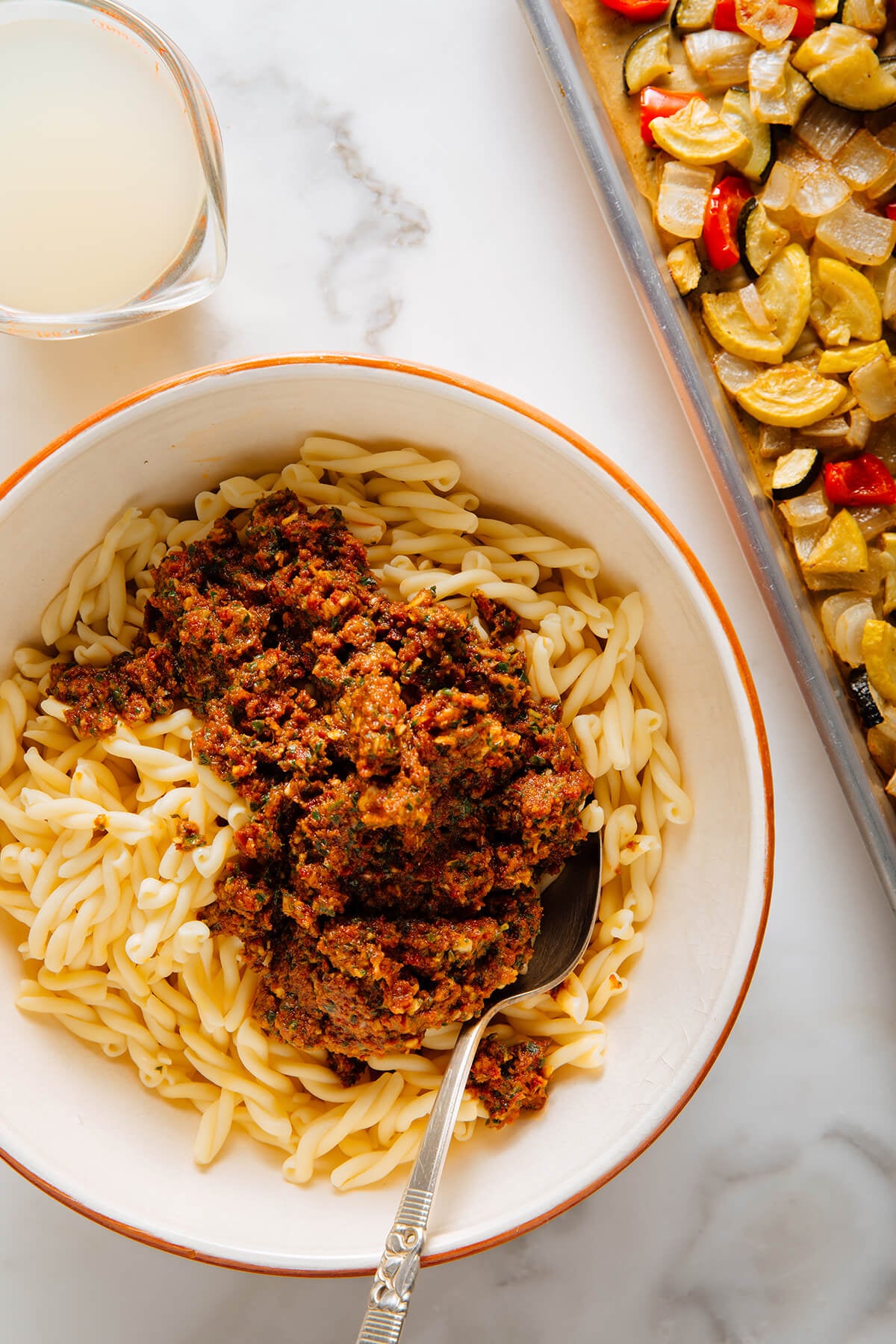 stirring red pesto into pasta